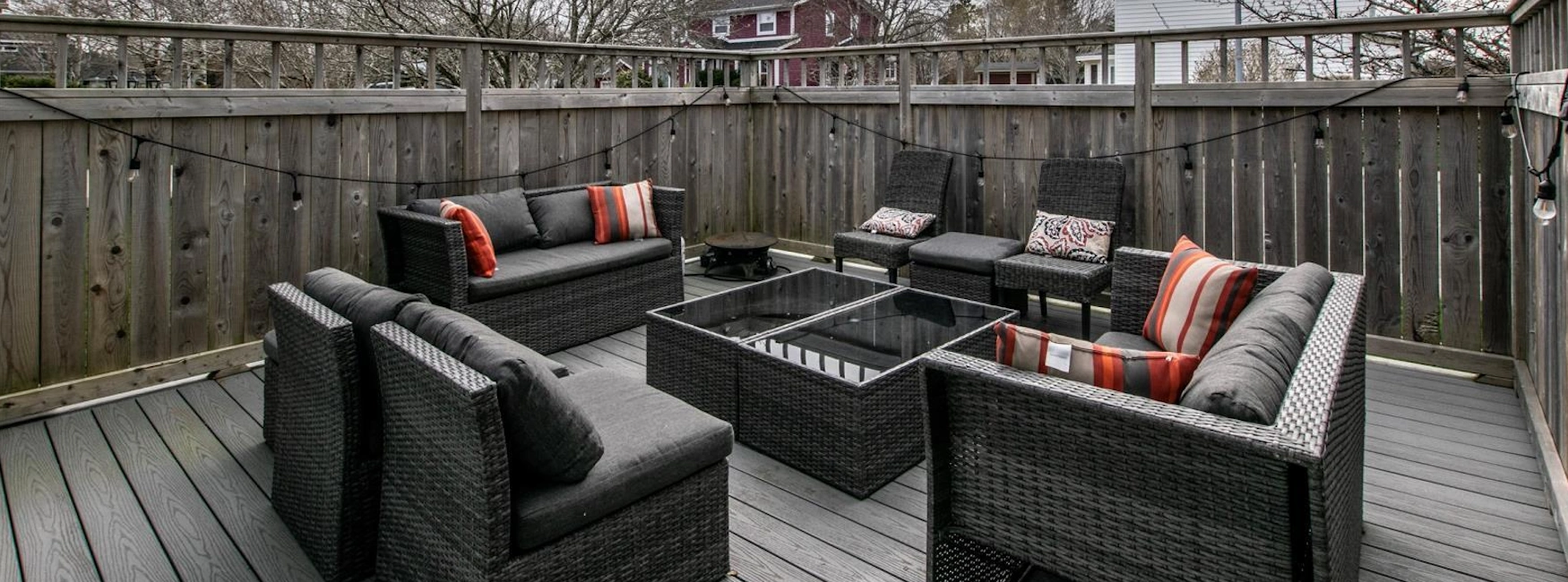 Bally Haly deck with grey wicker sofas, striped pillows and string lights.