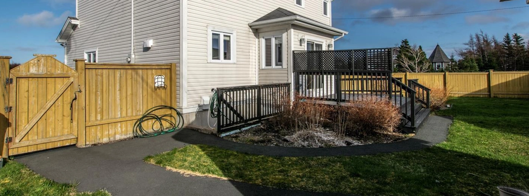 Brookfield Plains deck: fenced patio with wicker benches, covered grill, shed, and grassy yard.