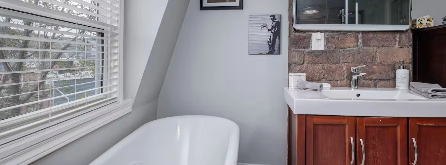 Interior of a stylish bathroom in downtown St. John's home, featuring a modern bathtub, brick accent wall, and elegant vanity.