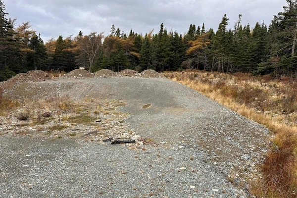Vacant land lot surrounded by mature trees and natural landscape, ideal for custom home building in Flatrock.