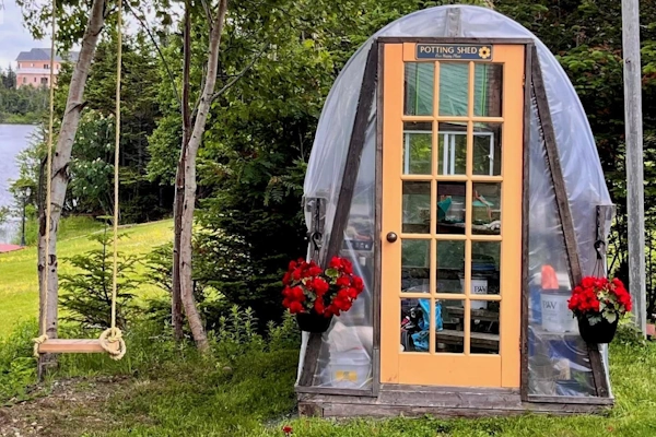 Charming backyard potting shed with hanging flowers and a lakeside view in Paradise, NL.