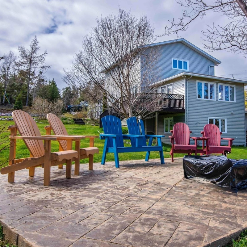 Outdoor patio with colorful Adirondack chairs in a spacious backyard in Paradise, NL.
