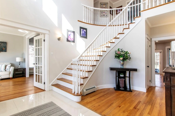 Elegant foyer with a grand staircase, hardwood floors, and natural light in a luxury home at King William Estates, St. John's