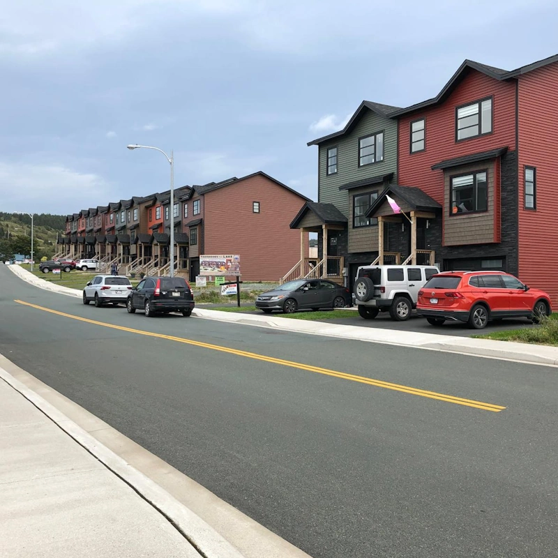 Row of modern, colorful townhouses and parked cars along a clean, quiet street—highlighting Pleasantville’s fresh housing options and community feel.