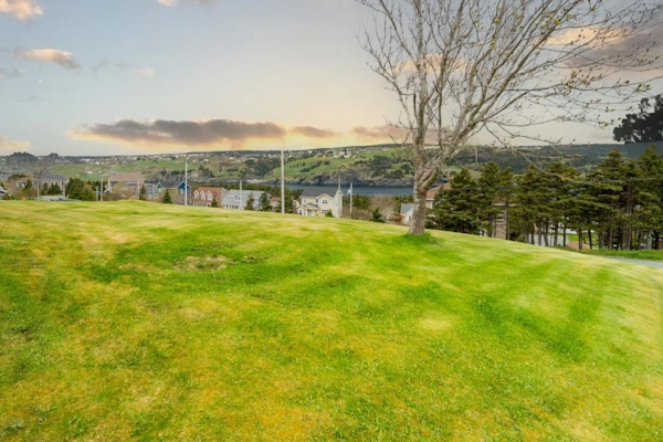 Expansive grassy yard with scenic views of rolling hills and distant waterfront in Torbay.