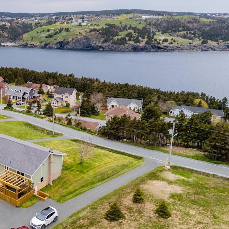 Aerial view of residential neighborhood in Torbay with picturesque waterfront and lush green surroundings.