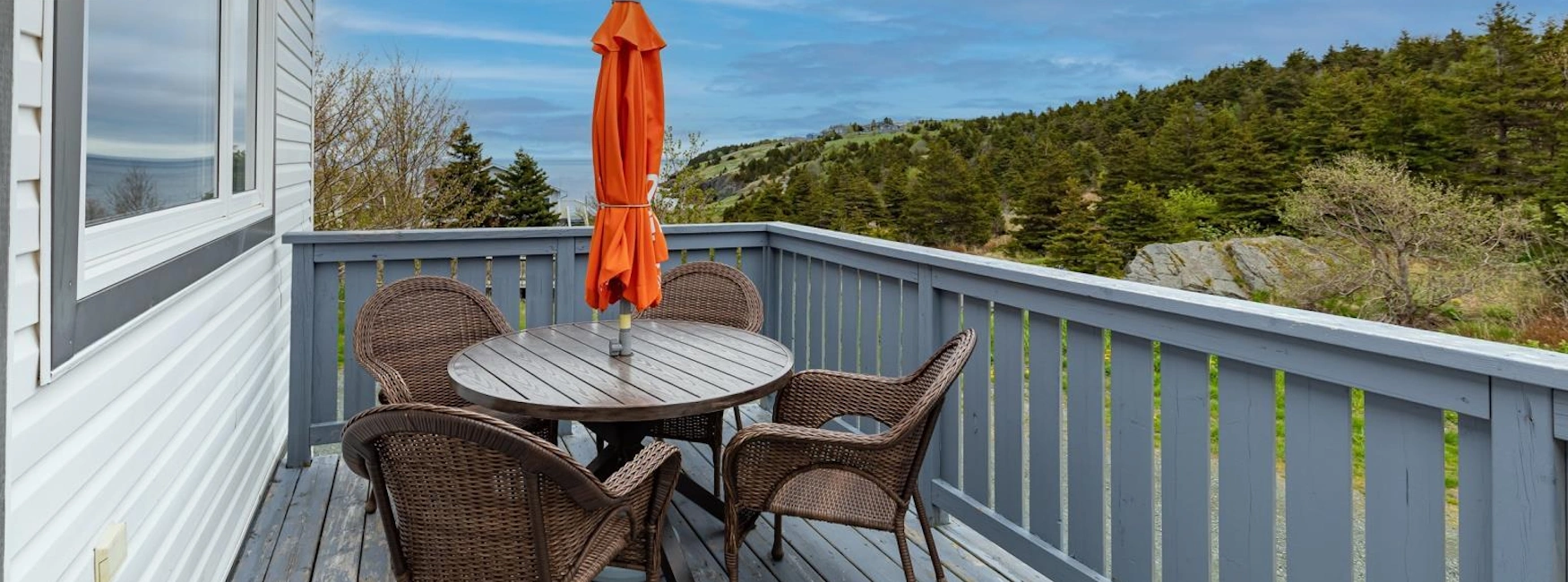 Cozy outdoor deck with seating area overlooking lush hills and ocean views in Torbay