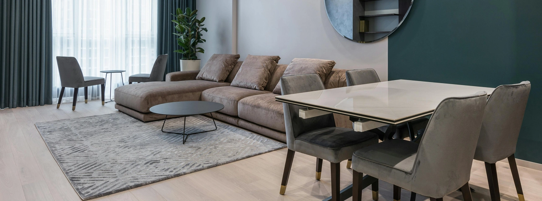 Contemporary condo living area with sofa, dining space, and large window.
